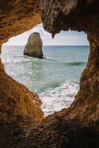 Scenic view of sea seen through rock formation against sky