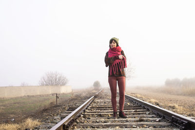 Woman standing on railroad track against clear sky