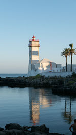 Lighthouse by sea against clear sky