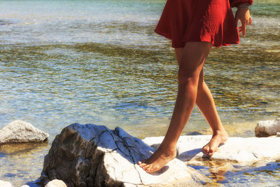 Low section of woman standing on rocks at beach