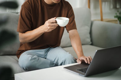 Midsection of woman using laptop at home