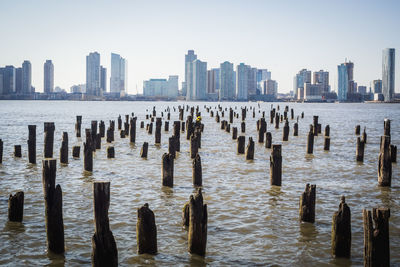 Wooden posts in sea against cityscape in new york city 
