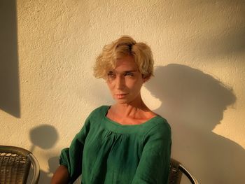 Close-up of woman looking away while sitting against wall