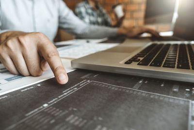 Midsection of man using laptop on table