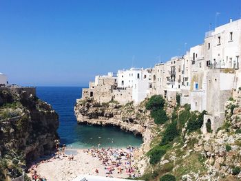 Scenic view of sea and buildings against clear blue sky