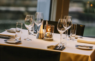 High angle view of wineglasses with plates and cutlery arranged on dining table at restaurant