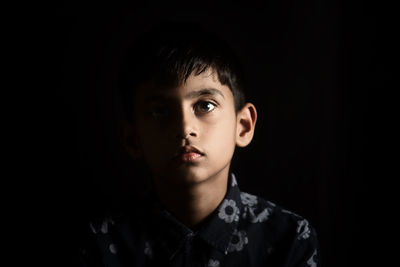 Close-up portrait of young man against black background