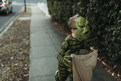 Portrait of boy holding umbrella standing on footpath