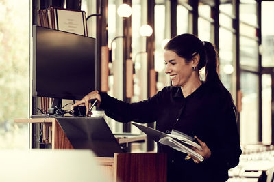 Smiling owner adjusting computer monitor in cafe
