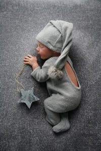 Cute newborn baby sleeping on gray blanket and holding craft wooden star. bed vibes.