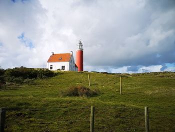 Lighthouse on field against sky