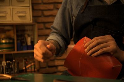Midsection of man sewing leather in workshop