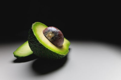 Half an avocado with a pit on a white table. contrast shot soft focus