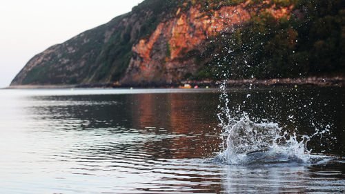 Splashed lake against mountain during sunset