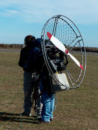 People with electric motor preparing for paragliding on land