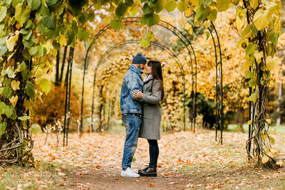 Two lovers are standing on an alley in an autumn park and hugging each other. autumn, love, 