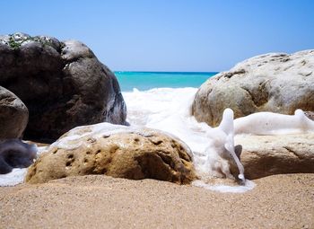 Rocks on beach against clear sky