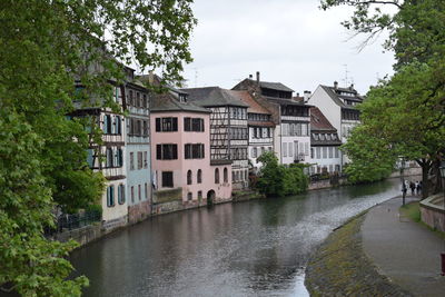 River amidst houses and buildings against sky