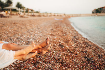 Low section of couple relaxing on beach