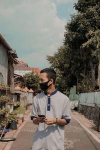 Young man standing by plants against sky