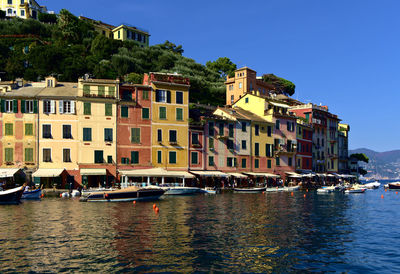 Buildings by river against sky in city