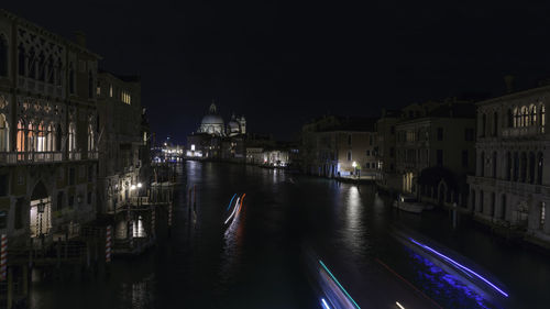 Canal amidst illuminated buildings in city at night