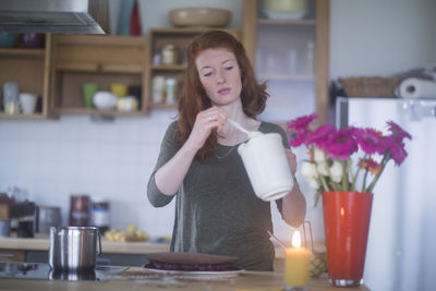 Young woman making birthday cake at home