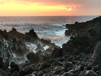 Scenic view of sea against dramatic sky during sunset