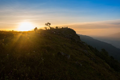 Man photographing on mountain during sunset