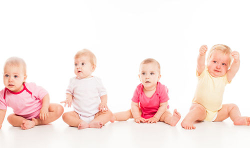 Portrait of cute baby boy sitting against white background