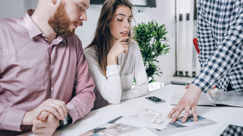 Young couple discussing over document while real estate agent explaining 