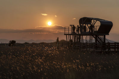 Silhouette people working on field against sky during sunset