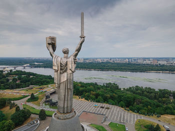 Statue by sea against sky in city