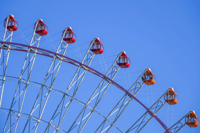 Low angle view of ferris wheel against clear blue sky