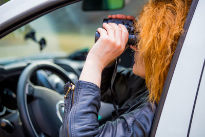 Woman using binoculars while sitting in car