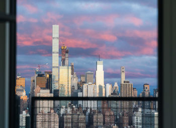 Digital composite image of buildings against cloudy sky