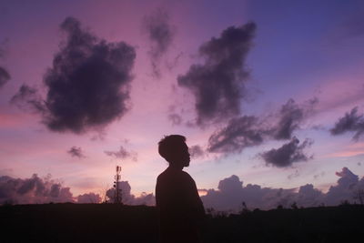 Silhouette man standing on field against sky during sunset