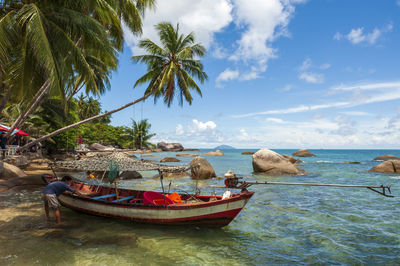 Man standing by boat in sea against sky