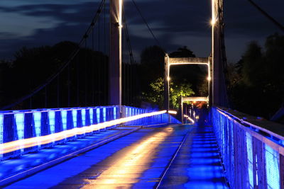 Illuminated footbridge against blue sky