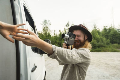 Boyfriend photographing girlfriend while standing by motor home