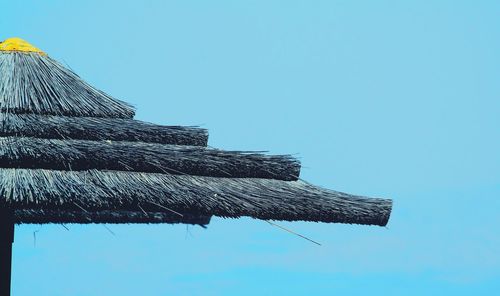 Close-up of cropped thatched roof against clear blue sky