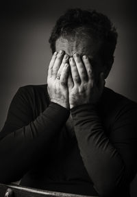 Depressed mature man covering face with hands while sitting at home 