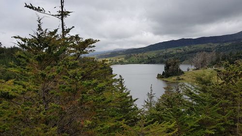 Scenic view of river by mountains against sky