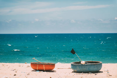 Deck chairs on beach against sky