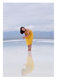 Woman standing on beach against sky