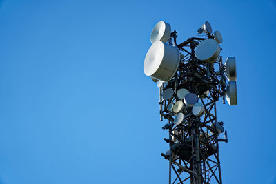 Low angle view of communications tower against clear blue sky