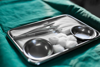 High angle view of cotton balls and equipment with bowls in tray on table in hospital