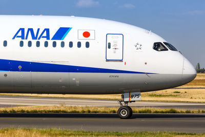 Close-up of airplane on airport runway against blue sky