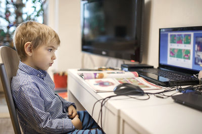 Side view of boy sitting on table