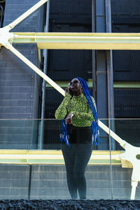 Woman holding umbrella against building in city